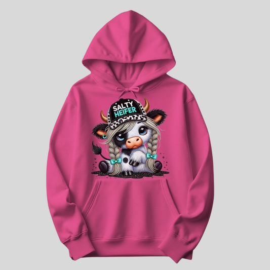 Heliconia pink hoodie featuring the same cartoon cow design with big eyes, braided hair, teal bows, and a cow print hat reading Salty Heifer