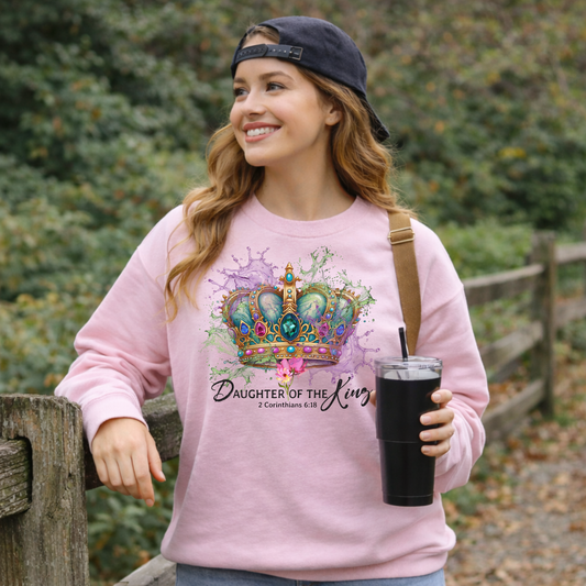 Light pink Daughter of the King sweatshirt worn by woman outdoors, Christian crown graphic faith sweatshirt