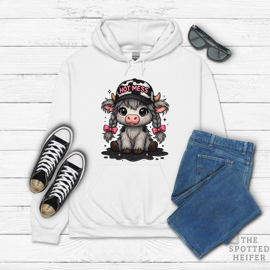 White hoodie flat lay with Hot Mess cow design, styled with black sneakers and blue jeans, The Spotted Heifer.